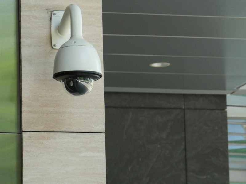 Close-up of a mounted security camera on a modern building's exterior.